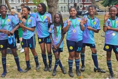 A girls' football team proudly showing their team kit