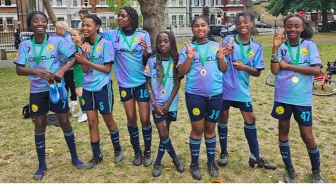 A girls' football team proudly showing their team kit